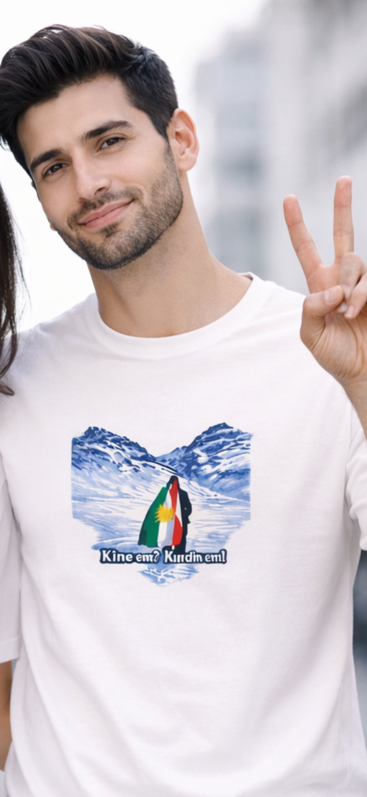 White t-shirt with snowy mountain landscape and Kurdish flag featuring the text “Kînem? Kurdim!”