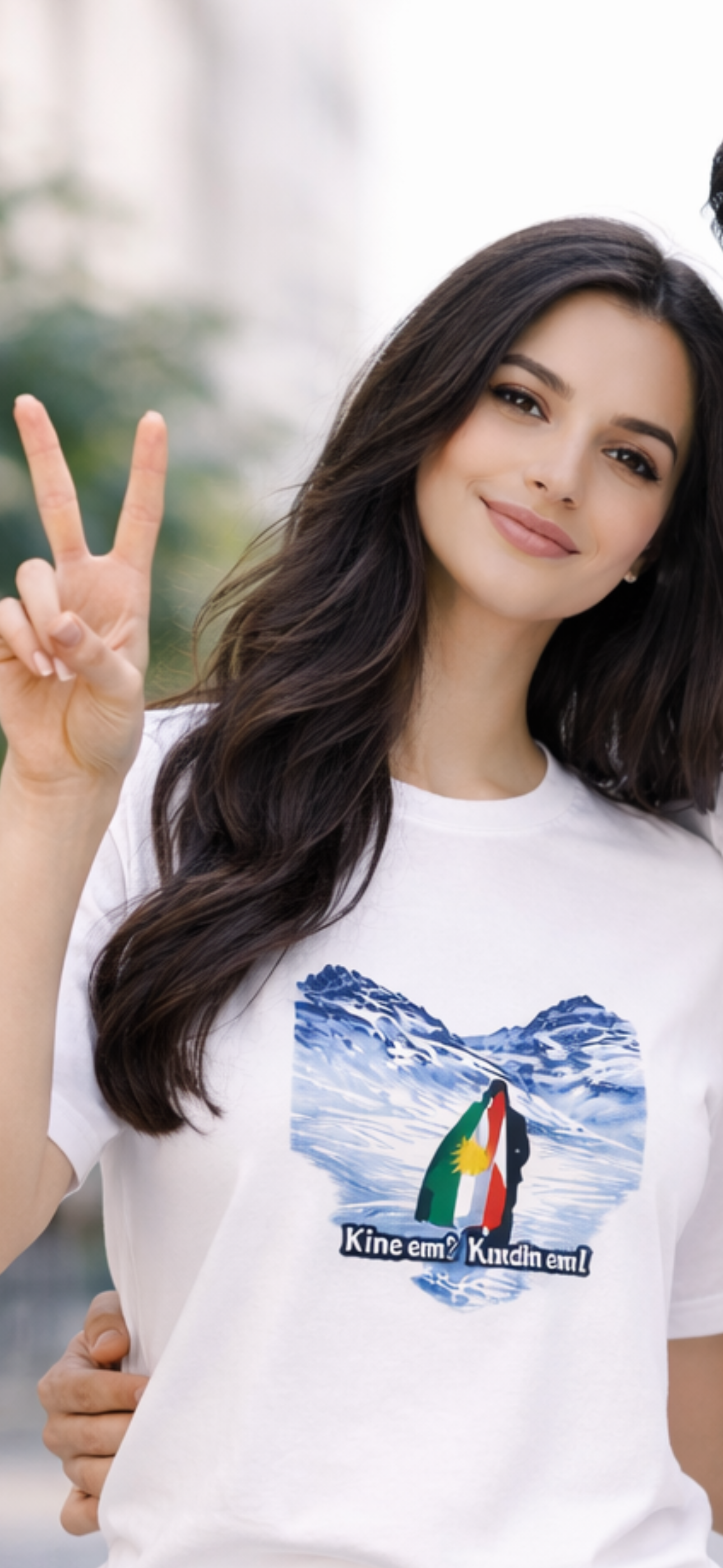 White t-shirt with snowy mountain landscape and Kurdish flag featuring the text “Kînem? Kurdim!”